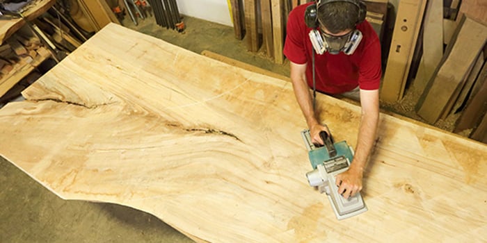 Urban Hardwoods craftsman sanding and prepping a section of trunk.